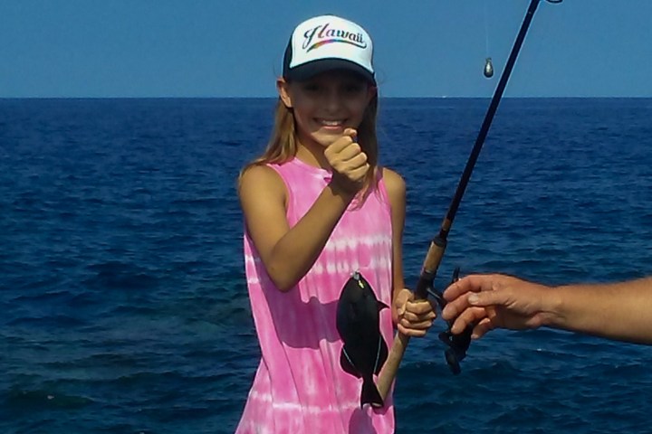 girl holding a fish at the ocean