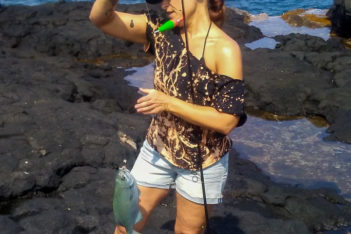 girl holding a fish on rocks